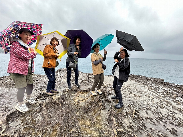 鬼ヶ城にて傘をさして楽しそうな熊野古道ツアー参加者たち